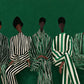 Emerald Assembly full artwork. Five seated figures wear contrasting striped garments against a deep emerald ground.