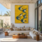 Saffron Swallows artwork displayed above a pale sectional beneath a concrete ceiling.