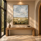 Cloudfield Stillness artwork displayed above a wooden console beside a window.