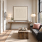 Quiet Fluting artwork displayed above a wooden console behind lounge seating.