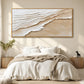 Sandy Tides artwork displayed above a bed with cream linen.