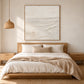 Quiet Foreshore artwork displayed above a bed with neutral linens and a wood headboard.