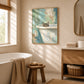 Bathside Peek artwork displayed beside a freestanding bathtub in a sunlit bathroom.