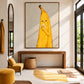 Banana Break artwork displayed above an entryway console beside a mirror and yellow chair.