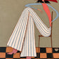 Scarlet Poise full artwork. A seated figure in flowing striped trousers rests beneath a sweeping scarlet hat.