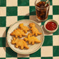 Dino Bites full artwork. Golden dinosaur-shaped nuggets sit beside a glass of cola and a small dish of ketchup.