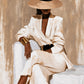 Ivory Composure full artwork. A seated woman in an ivory suit rests beneath a wide-brimmed hat, her face partly hidden in shadow.