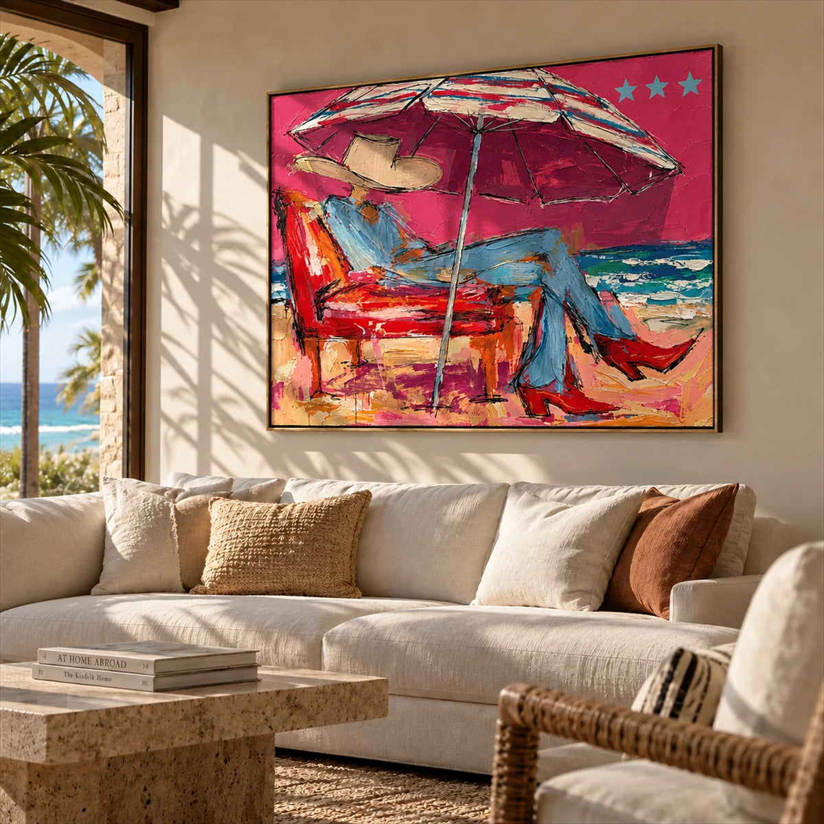 Parasol Escape artwork displayed above a cream sofa beside a coastal window.
